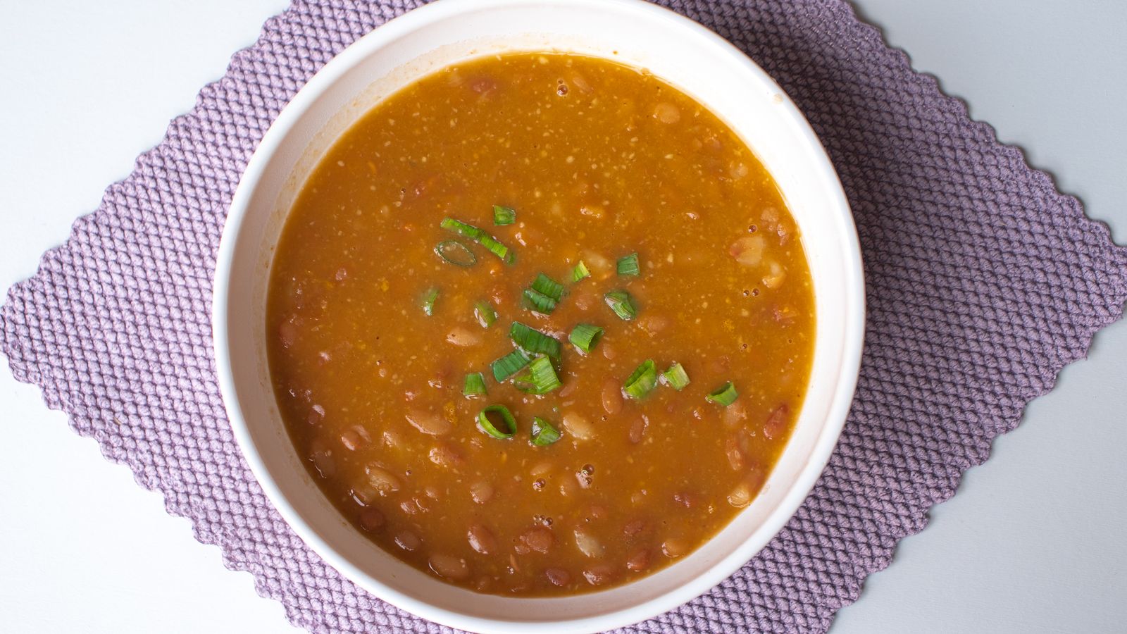 Bol de haricots blancs cuisinés en soupe-repas maison, servi sur une table chaleureuse.