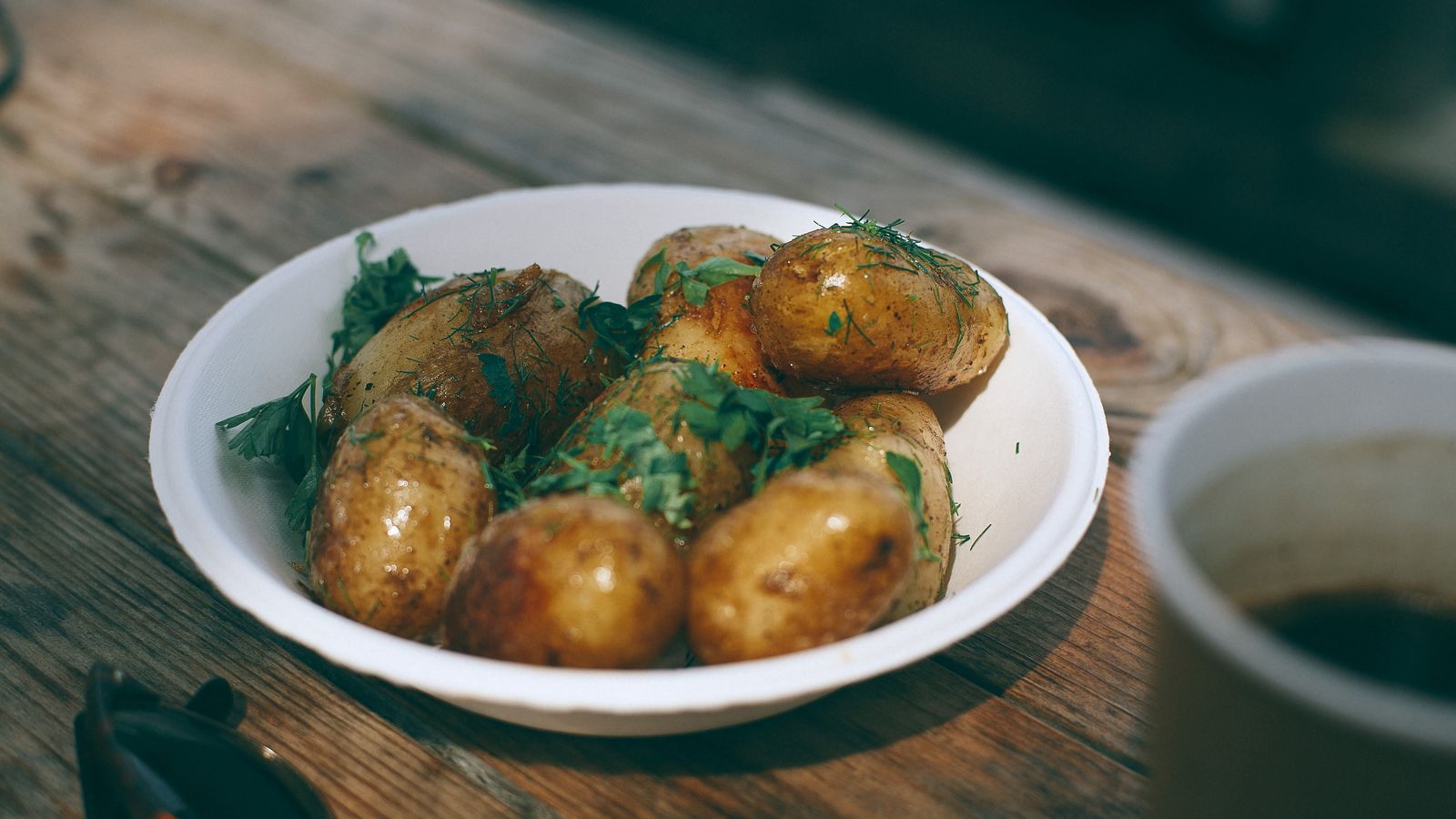 Pommes de terre déjà cuites garnies d’herbes dans un bol rustique, prêtes à être transformées en nouveau repas.