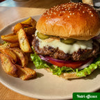 Burger maison avec steak, fromage, salade, tomate, oignon rouge, cornichons et pommes de terre rôties pour un repas familial