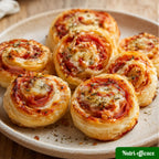 Roulés feuilletés apéritifs garnis de jambon, tomate et fromage, dorés au four et servis sur une assiette.